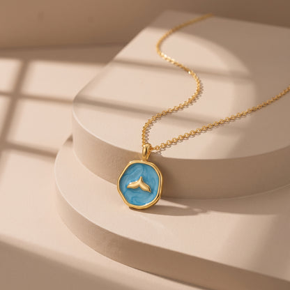 collar cola de ballena dorado y azul sobre plataforma elegante